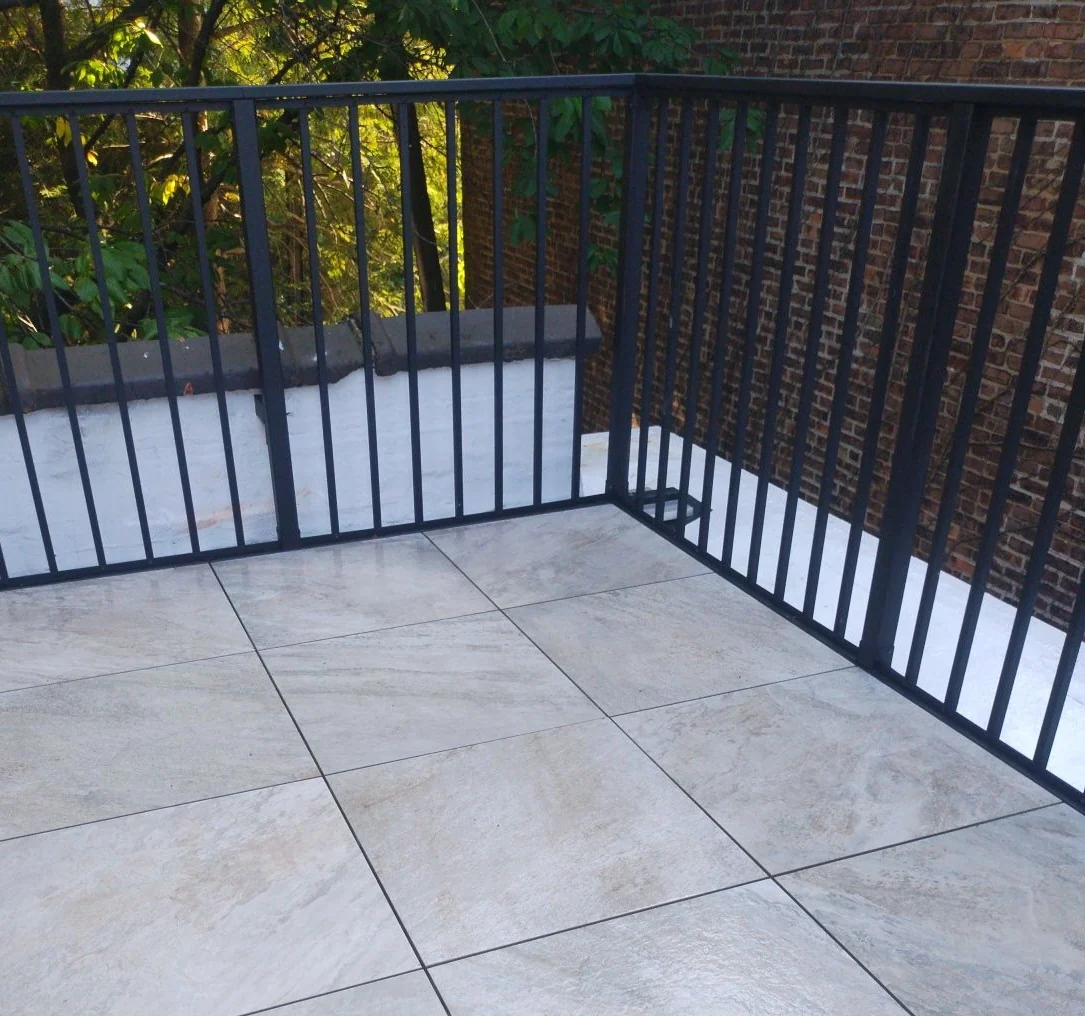 Stone-look porcelain pavers on a compact balcony with black metal railing