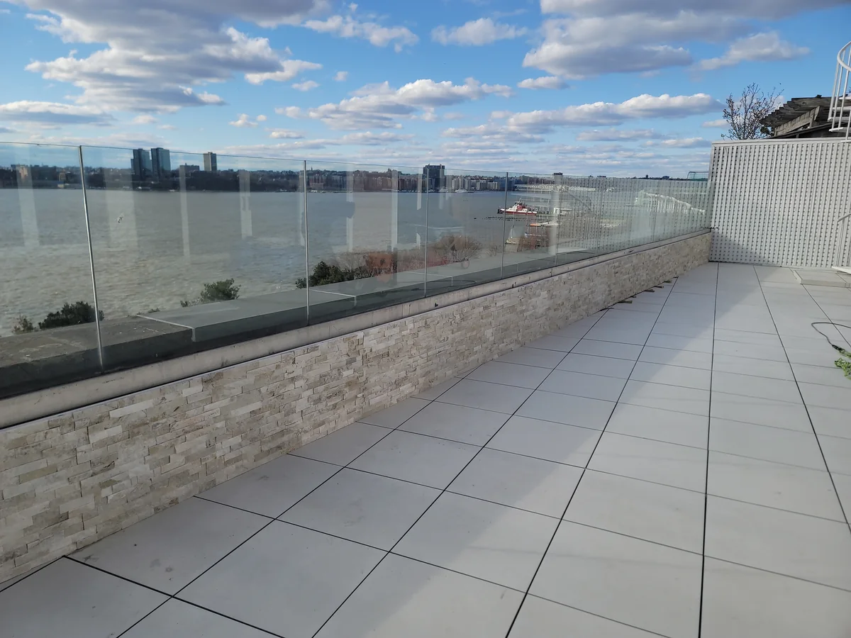 Light porcelain paver terrace with glass railing and river views