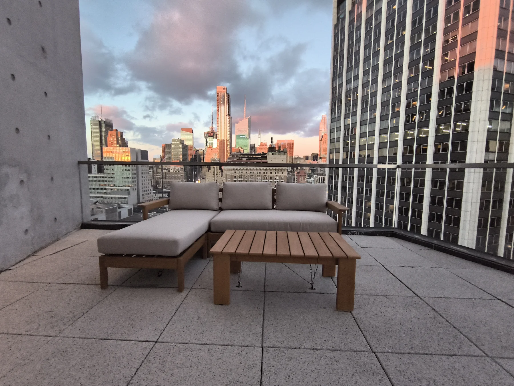 Light-gray porcelain paver terrace with outdoor furniture and sunset skyline
